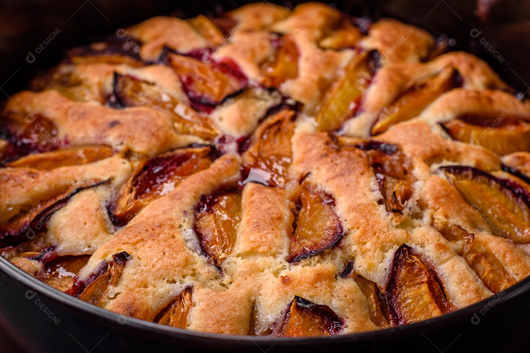 Deliciosa torta caseira aromática doce com ameixas maduras sobre um fundo escuro de concreto