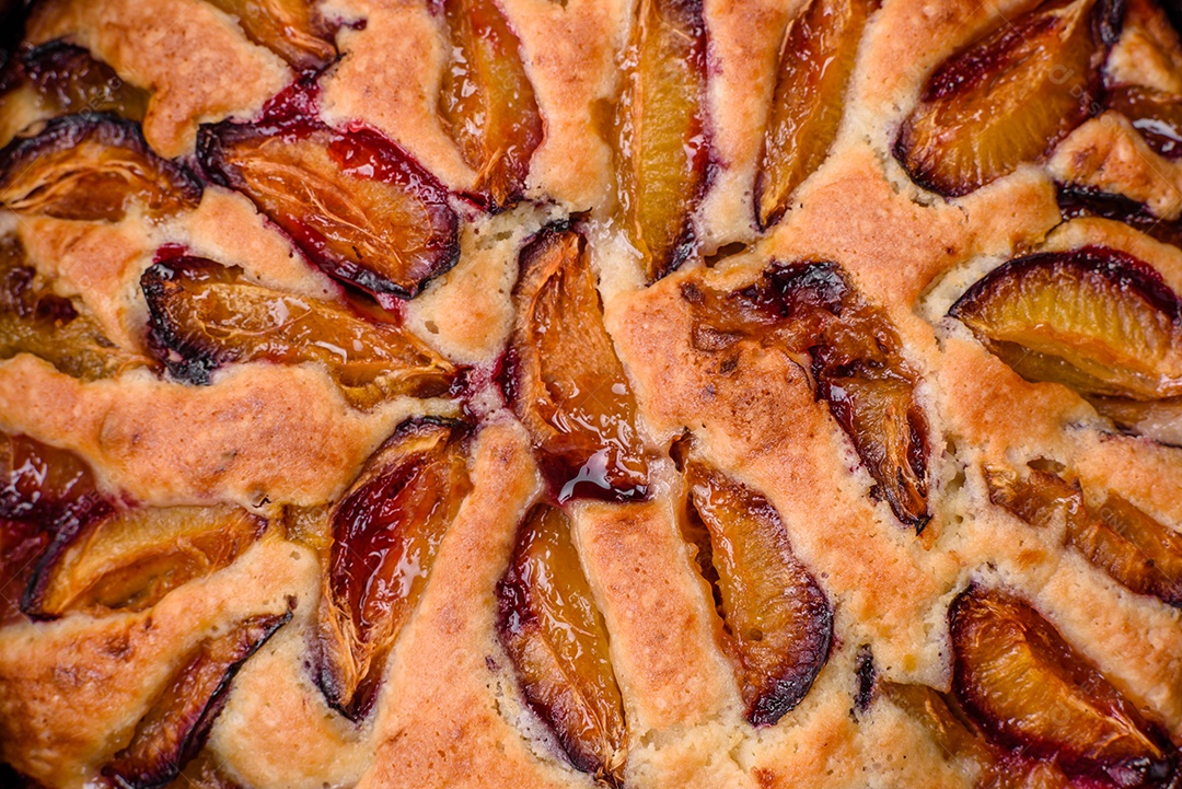Deliciosa torta caseira aromática doce com ameixas maduras sobre um fundo escuro de concreto