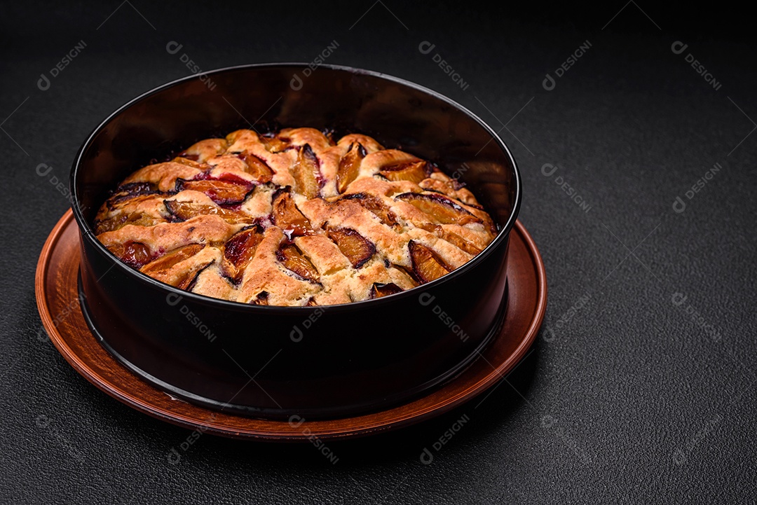 Deliciosa torta caseira aromática doce com ameixas maduras sobre um fundo escuro de concreto