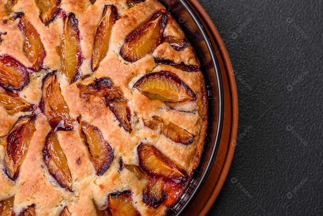 Deliciosa torta caseira aromática doce com ameixas maduras sobre um fundo escuro de concreto