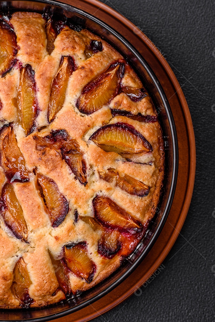 Deliciosa torta caseira aromática doce com ameixas maduras sobre um fundo escuro de concreto