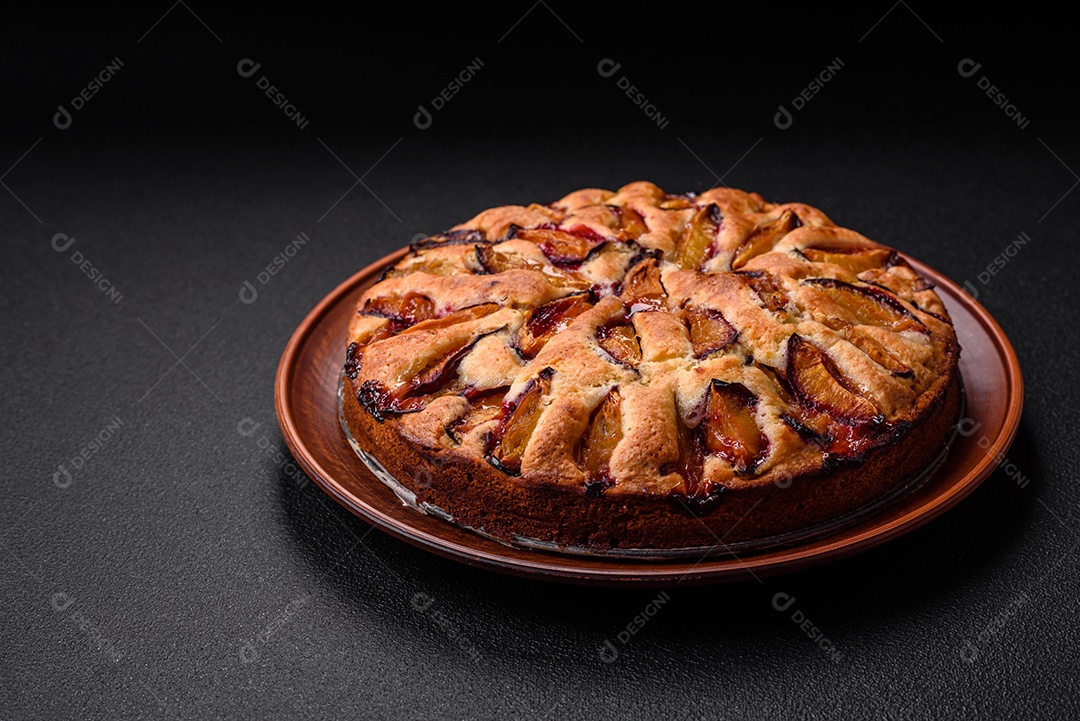 Deliciosa torta caseira aromática doce com ameixas maduras sobre um fundo escuro de concreto