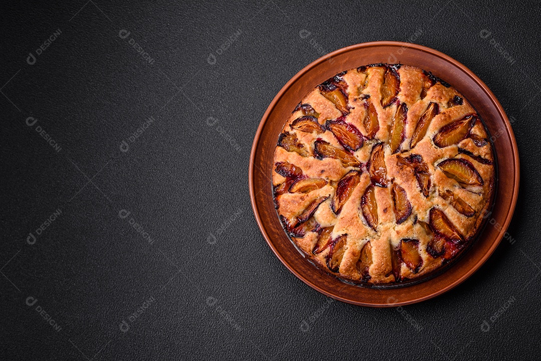 Deliciosa torta caseira aromática doce com ameixas maduras sobre um fundo escuro de concreto