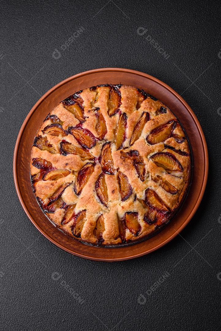 Deliciosa torta caseira aromática doce com ameixas maduras sobre um fundo escuro de concreto