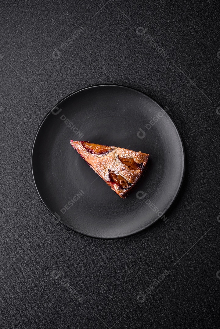 Deliciosa torta caseira aromática doce com ameixas maduras sobre um fundo escuro de concreto