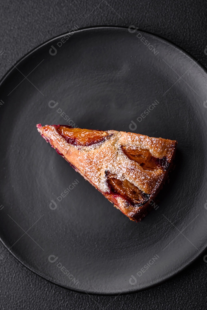 Deliciosa torta caseira aromática doce com ameixas maduras sobre um fundo escuro de concreto