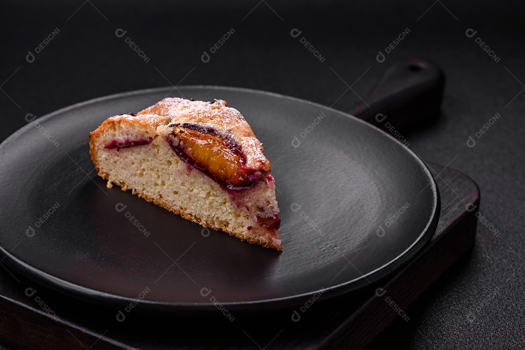 Deliciosa torta caseira aromática doce com ameixas maduras sobre um fundo escuro de concreto