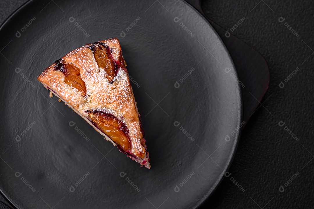 Deliciosa torta caseira aromática doce com ameixas maduras sobre um fundo escuro de concreto