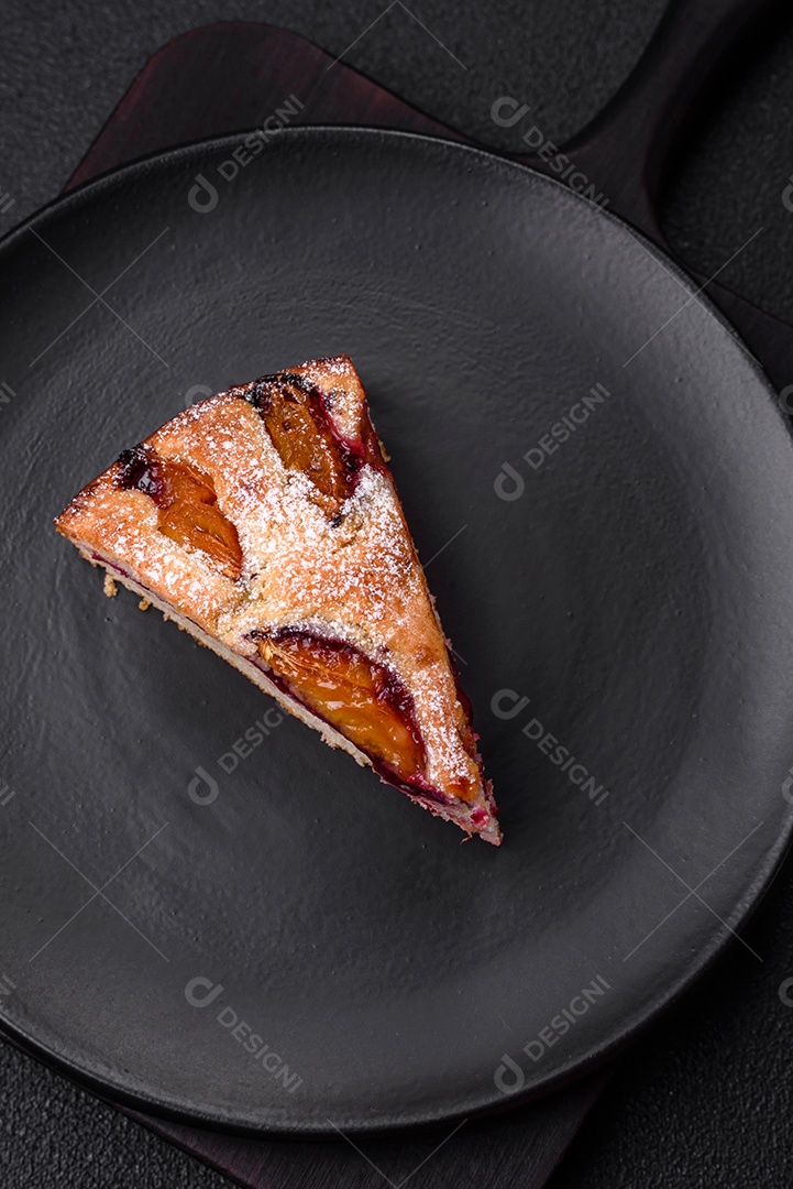 Deliciosa torta caseira aromática doce com ameixas maduras sobre um fundo escuro de concreto
