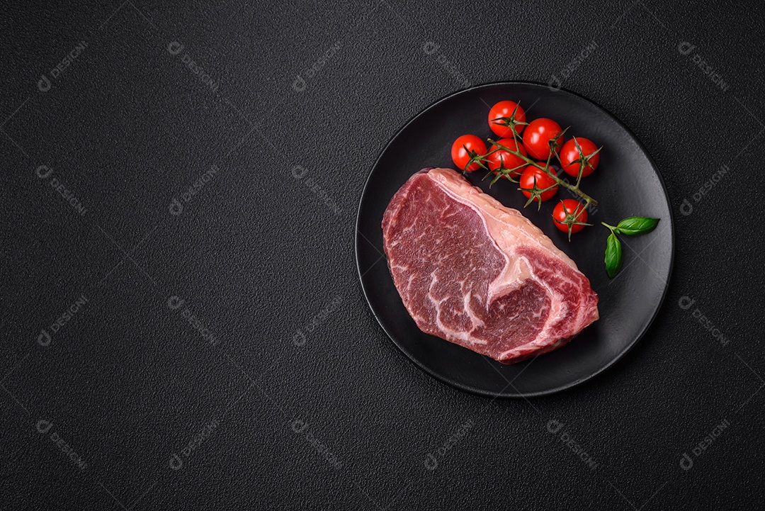 Bife de carne crua fresca com sal, especiarias e ervas sobre um fundo escuro de concreto