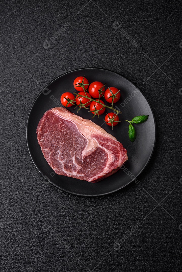 Bife de carne crua fresca com sal, especiarias e ervas sobre um fundo escuro de concreto