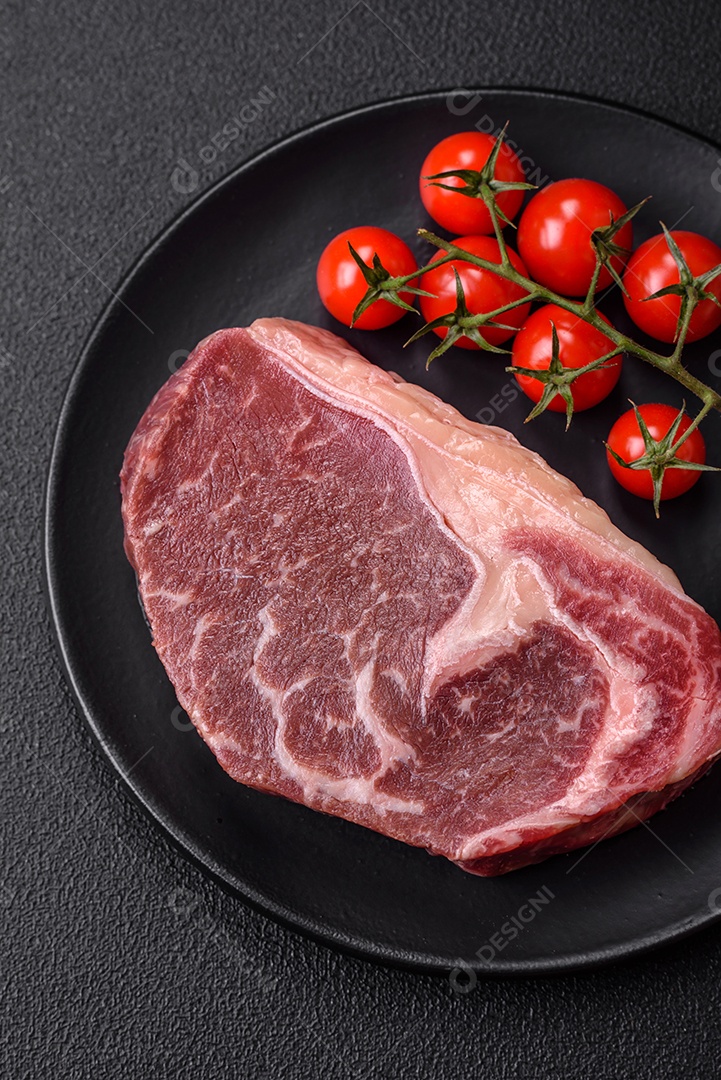 Bife de carne crua fresca com sal, especiarias e ervas sobre um fundo escuro de concreto