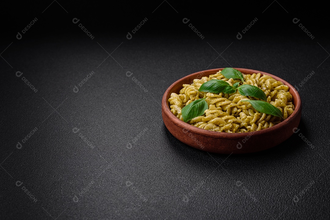 Deliciosa massa fresca com molho pesto verde com manjericão, sal e especiarias sobre fundo escuro de concreto