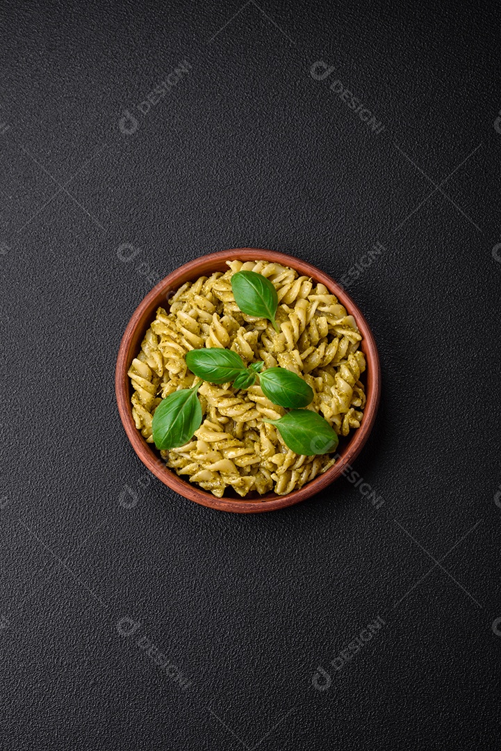 Deliciosa massa fresca com molho pesto verde com manjericão, sal e especiarias sobre fundo escuro de concreto