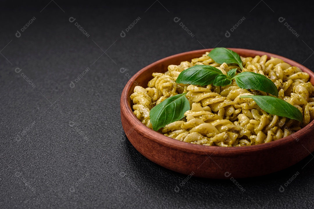 Deliciosa massa fresca com molho pesto verde com manjericão, sal e especiarias sobre fundo escuro de concreto