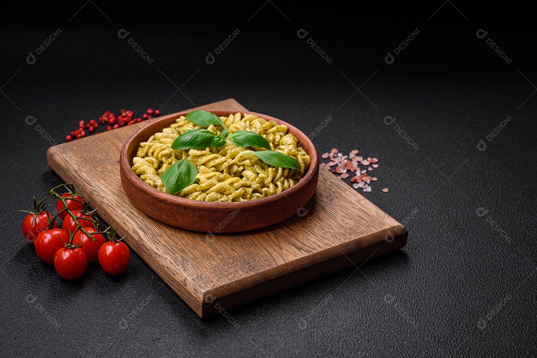 Deliciosa massa fresca com molho pesto verde com manjericão, sal e especiarias sobre fundo escuro de concreto