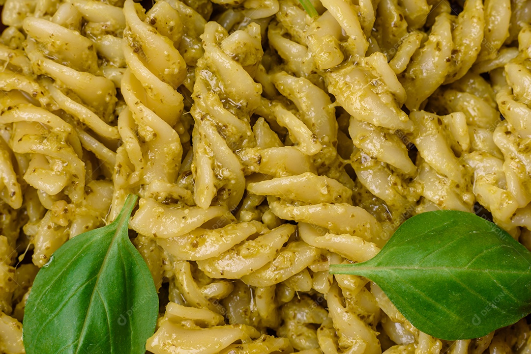 Deliciosa massa fresca com molho pesto verde com manjericão, sal e especiarias sobre fundo escuro de concreto