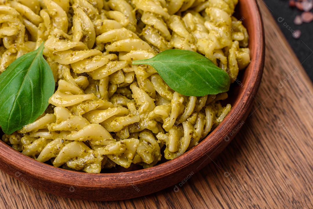 Deliciosa massa fresca com molho pesto verde com manjericão, sal e especiarias sobre fundo escuro de concreto