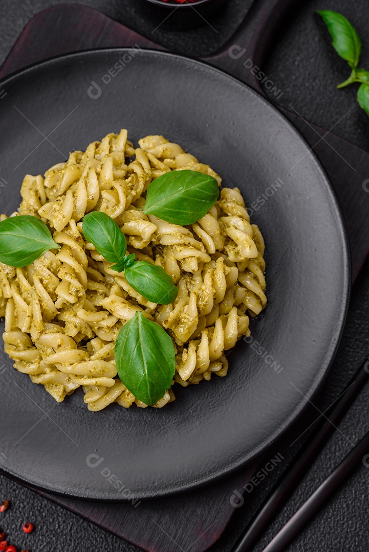 Deliciosa massa fresca com molho pesto verde com manjericão, sal e especiarias sobre fundo escuro de concreto