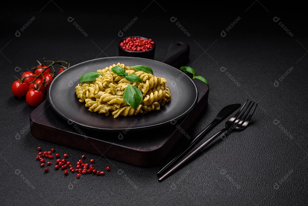 Deliciosa massa fresca com molho pesto verde com manjericão, sal e especiarias sobre fundo escuro de concreto