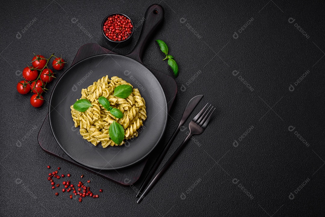 Deliciosa massa fresca com molho pesto verde com manjericão, sal e especiarias sobre fundo escuro de concreto