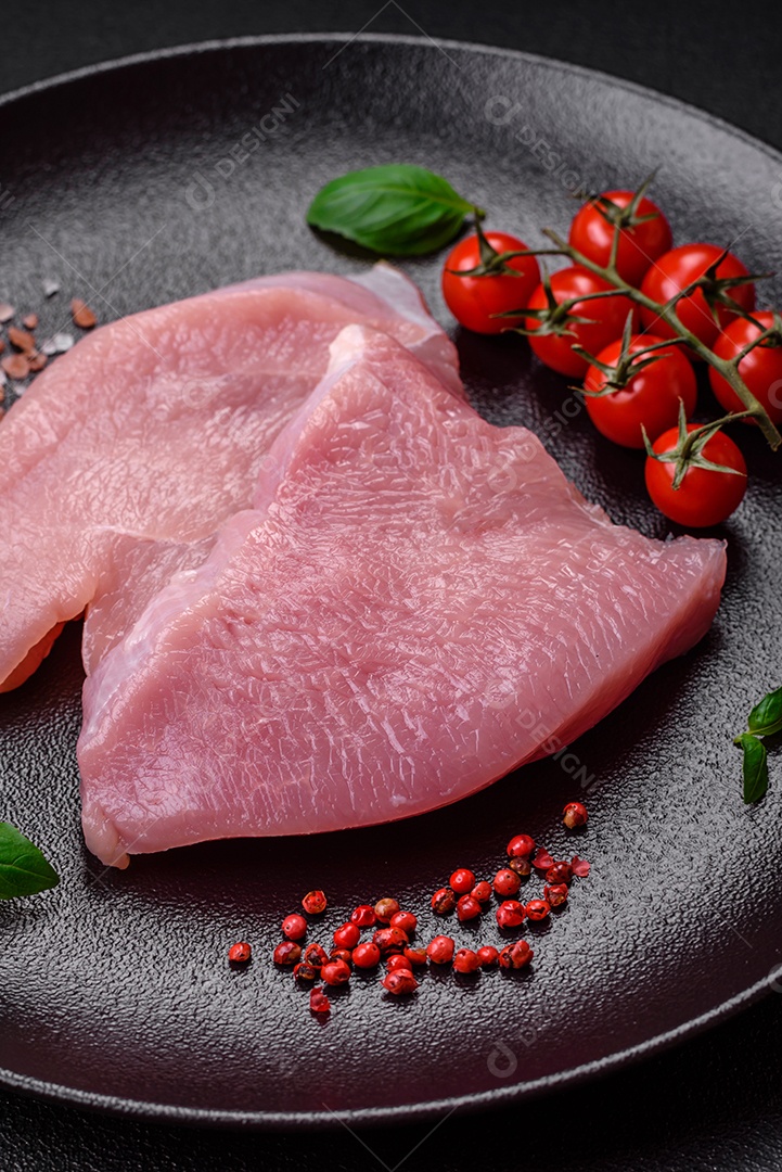 Bife de filé mignon cru com sal, especiarias e ervas em um fundo escuro de concreto