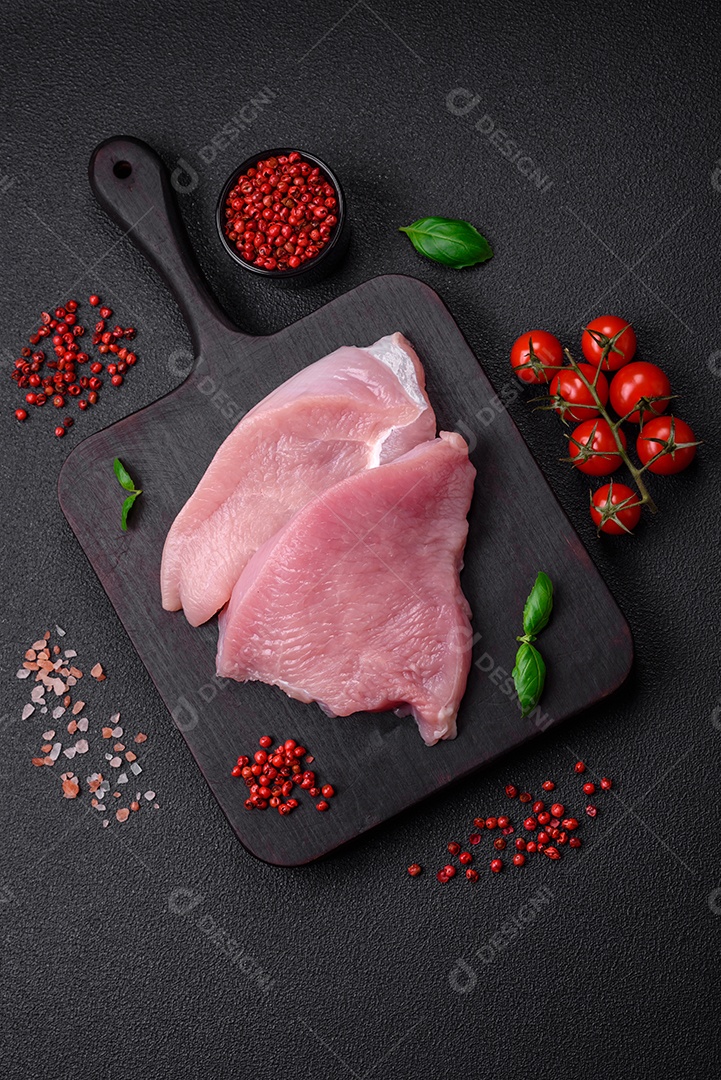 Carne de peru crua em forma de fatias com sal, especiarias e ervas sobre um fundo escuro de concreto