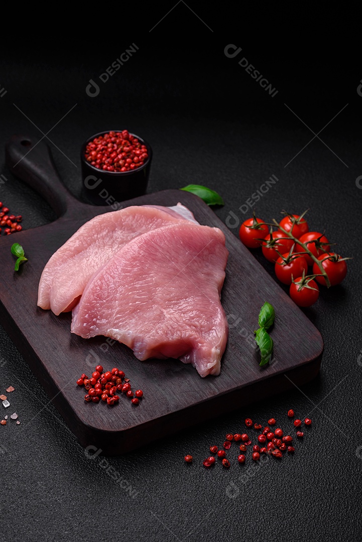 Carne de peru crua em forma de fatias com sal, especiarias e ervas sobre um fundo escuro de concreto