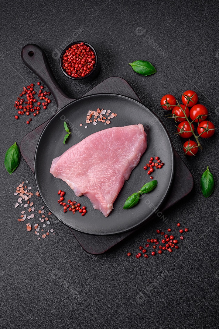 Carne de peru crua em forma de fatias com sal, especiarias e ervas sobre um fundo escuro de concreto