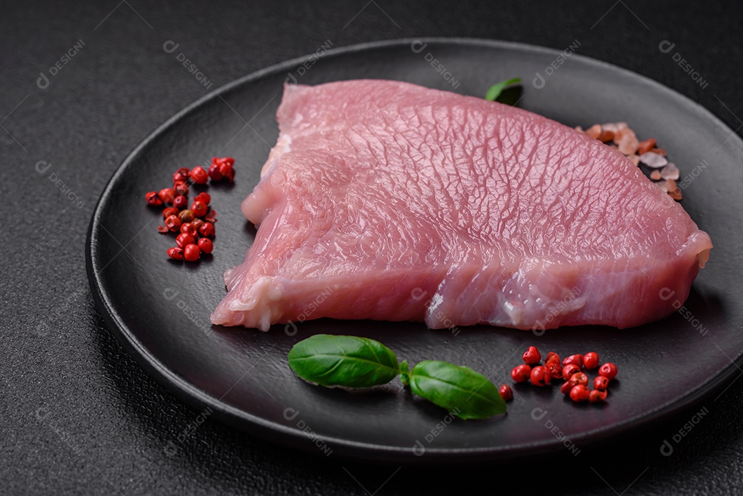 Carne de peru crua em forma de fatias com sal, especiarias e ervas sobre um fundo escuro de concreto