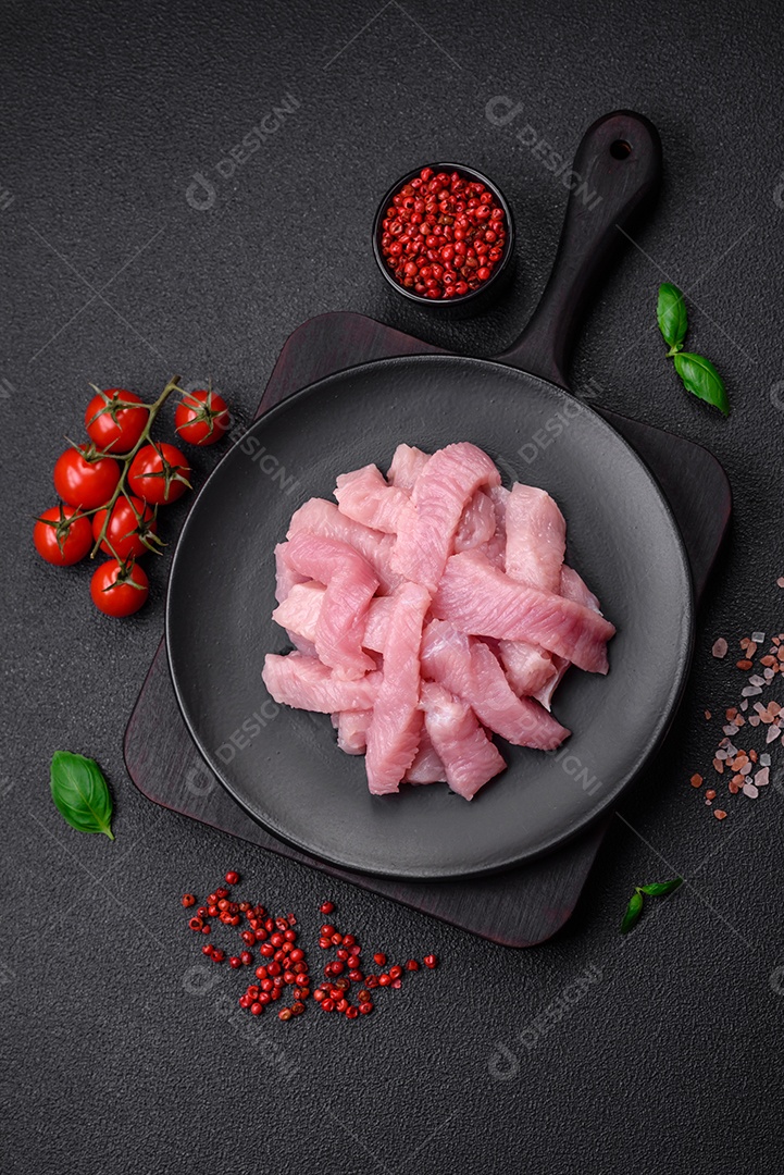 Carne de peru crua em forma de fatias com sal, especiarias e ervas sobre um fundo escuro de concreto