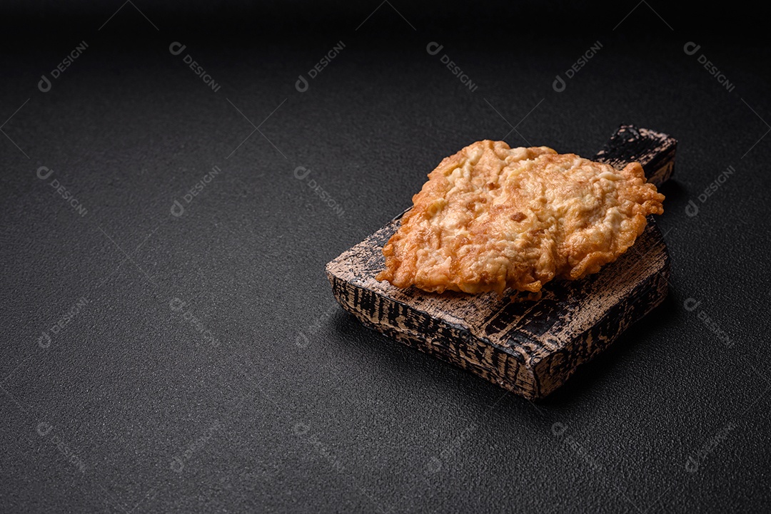 Deliciosa costeleta de frango frito ou carne de porco frita à milanesa com sal, especiarias e ervas sobre um fundo escuro de concreto