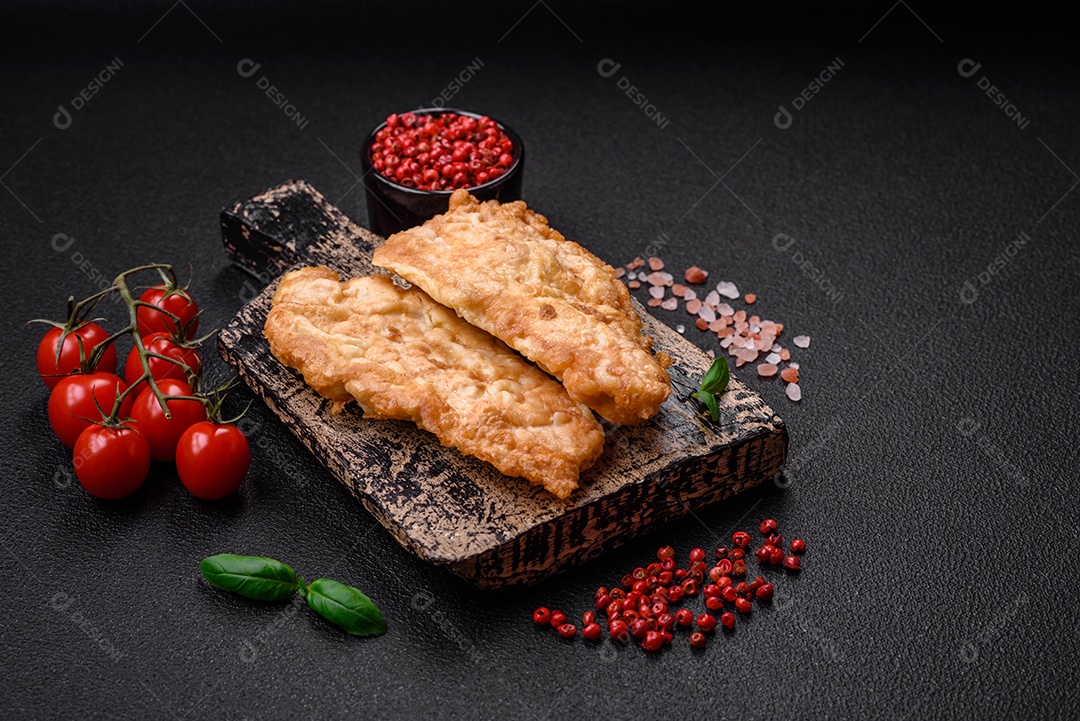 Deliciosa costeleta de frango frito ou carne de porco frita à milanesa com sal, especiarias e ervas sobre um fundo escuro de concreto