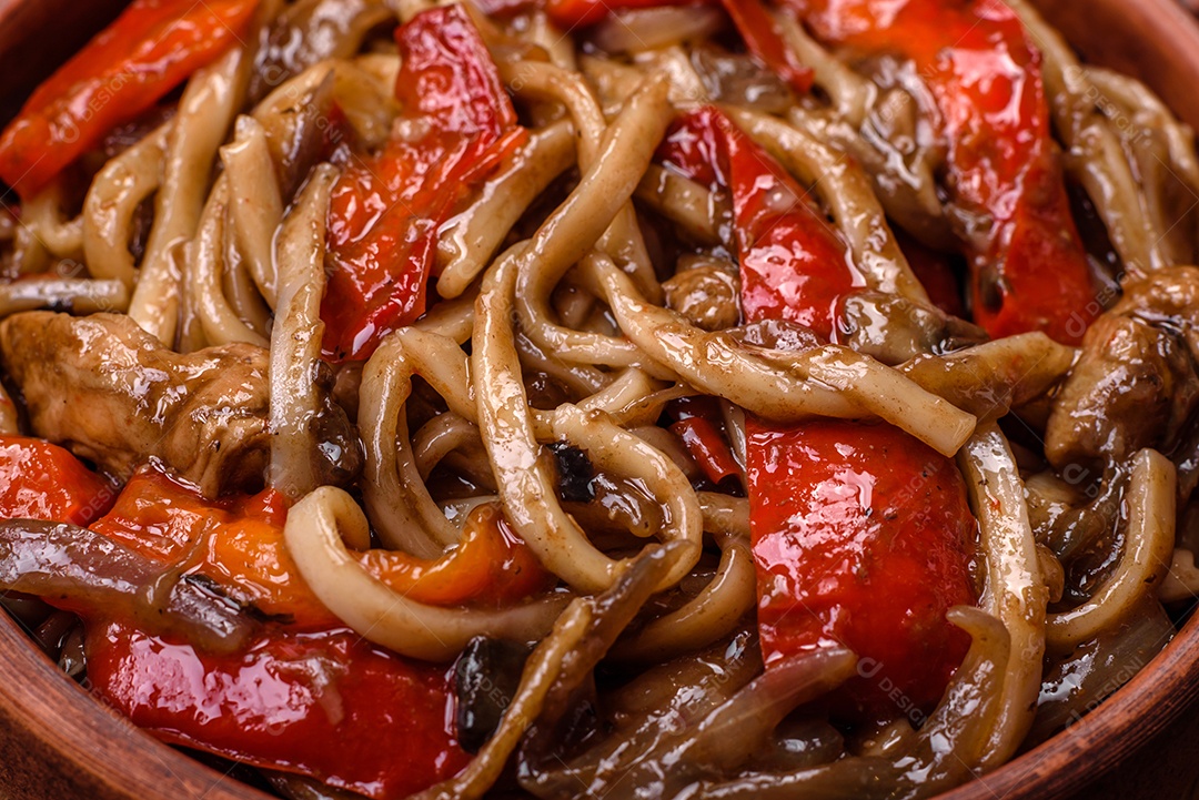 Delicioso prato de udon asiático com legumes, cogumelos, sal e especiarias numa placa cerâmica sobre um fundo escuro de concreto