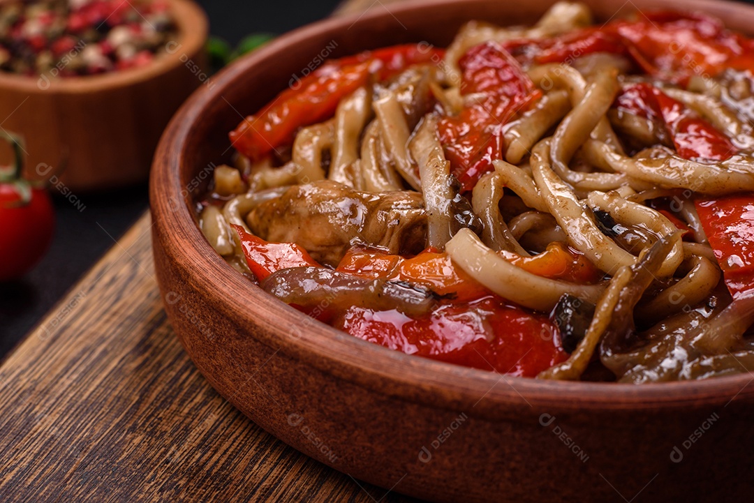 Delicioso prato de udon asiático com legumes, cogumelos, sal e especiarias numa placa cerâmica sobre um fundo escuro de concreto