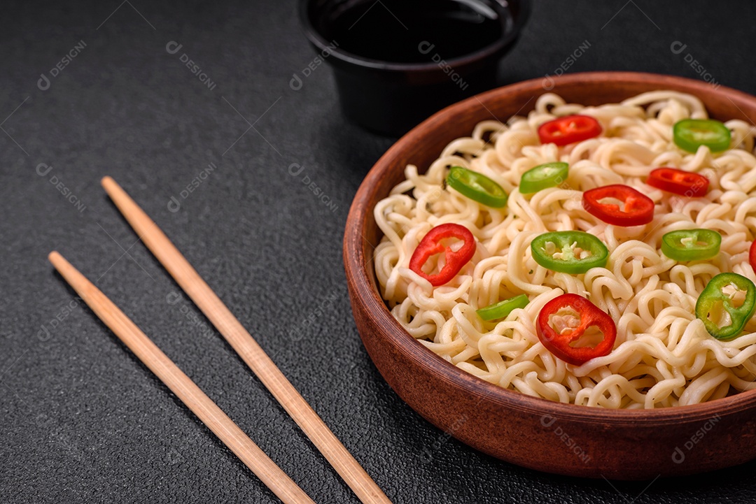 Delicioso prato de cozinha asiática com macarrão de arroz, pimentão, cogumelos e especiarias sobre fundo escuro de concreto