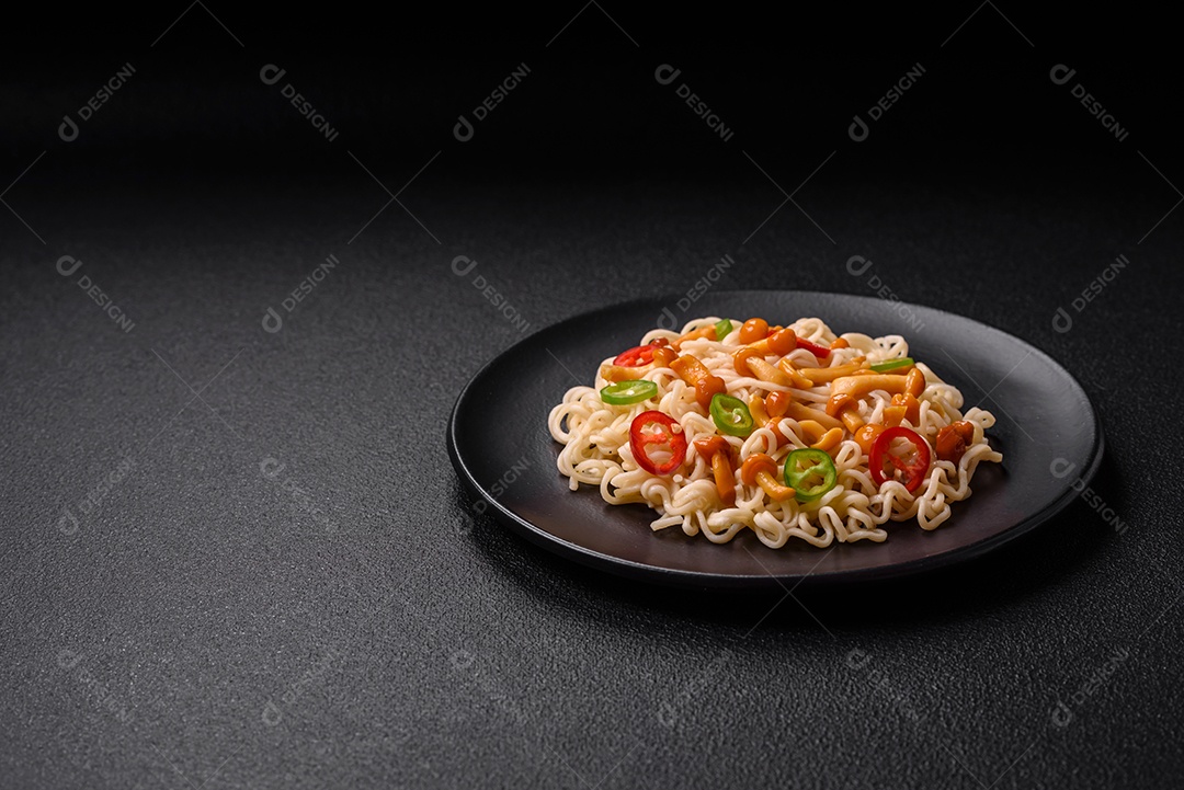 Delicioso prato de cozinha asiática com macarrão de arroz, pimentão, cogumelos e especiarias sobre fundo escuro de concreto