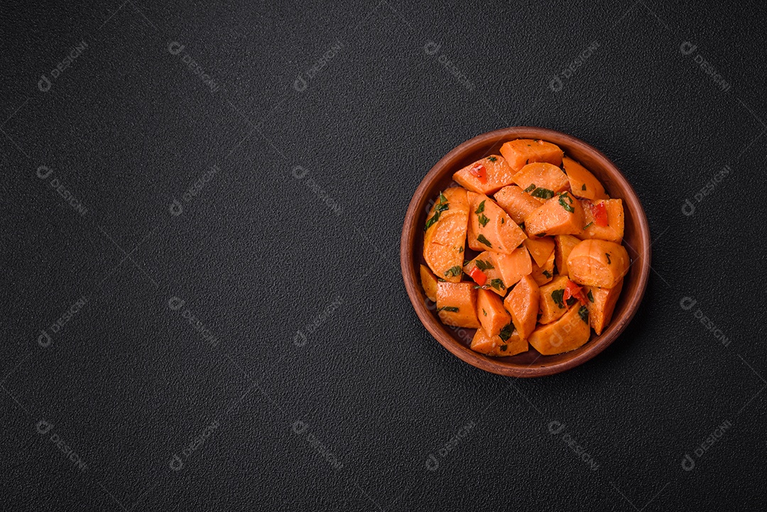 Deliciosa batata-doce cozida com cubos de sal, especiarias e ervas em uma placa cerâmica sobre um fundo escuro de concreto