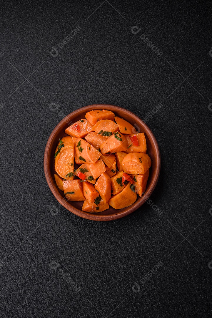 Deliciosa batata-doce cozida com cubos de sal, especiarias e ervas em uma placa cerâmica sobre um fundo escuro de concreto