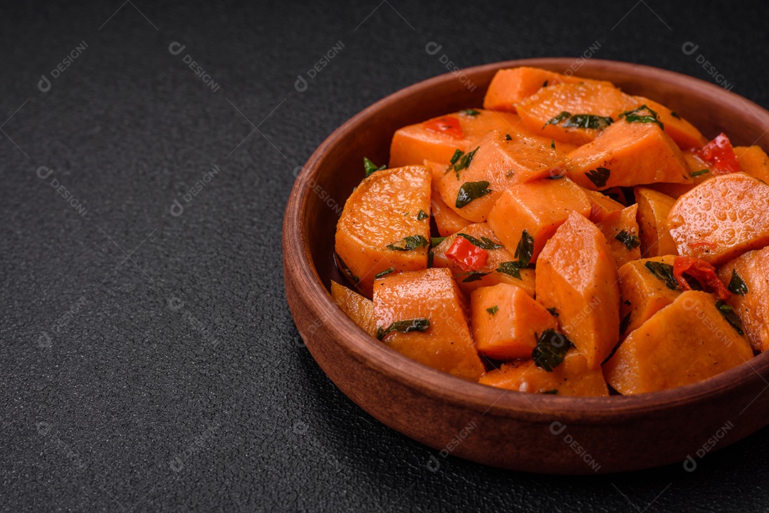 Deliciosa batata-doce cozida com cubos de sal, especiarias e ervas em uma placa cerâmica sobre um fundo escuro de concreto