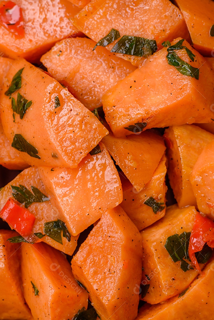 Deliciosa batata-doce cozida com cubos de sal, especiarias e ervas em uma placa cerâmica sobre um fundo escuro de concreto