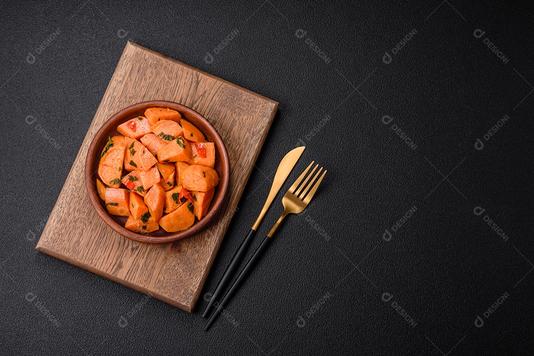 Deliciosa batata-doce cozida com cubos de sal, especiarias e ervas em uma placa cerâmica sobre um fundo escuro de concreto