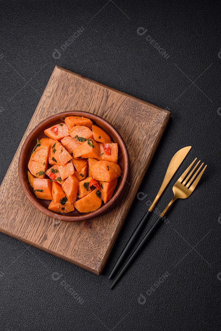 Deliciosa batata-doce cozida com cubos de sal, especiarias e ervas em uma placa cerâmica sobre um fundo escuro de concreto