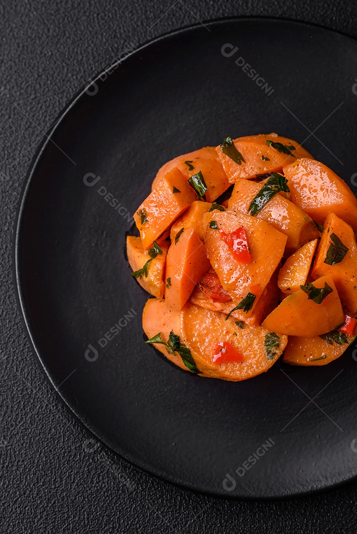 Deliciosa batata-doce cozida com cubos de sal, especiarias e ervas em uma placa cerâmica sobre um fundo escuro de concreto