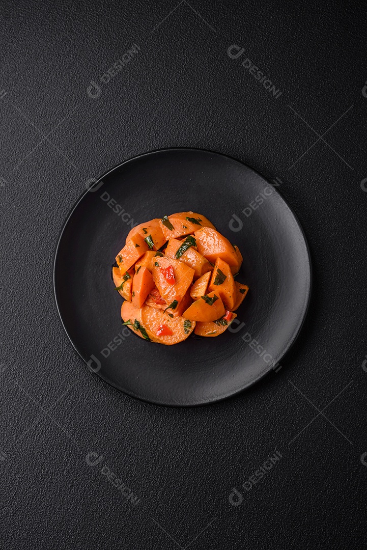 Deliciosa batata-doce cozida com cubos de sal, especiarias e ervas em uma placa cerâmica sobre um fundo escuro de concreto