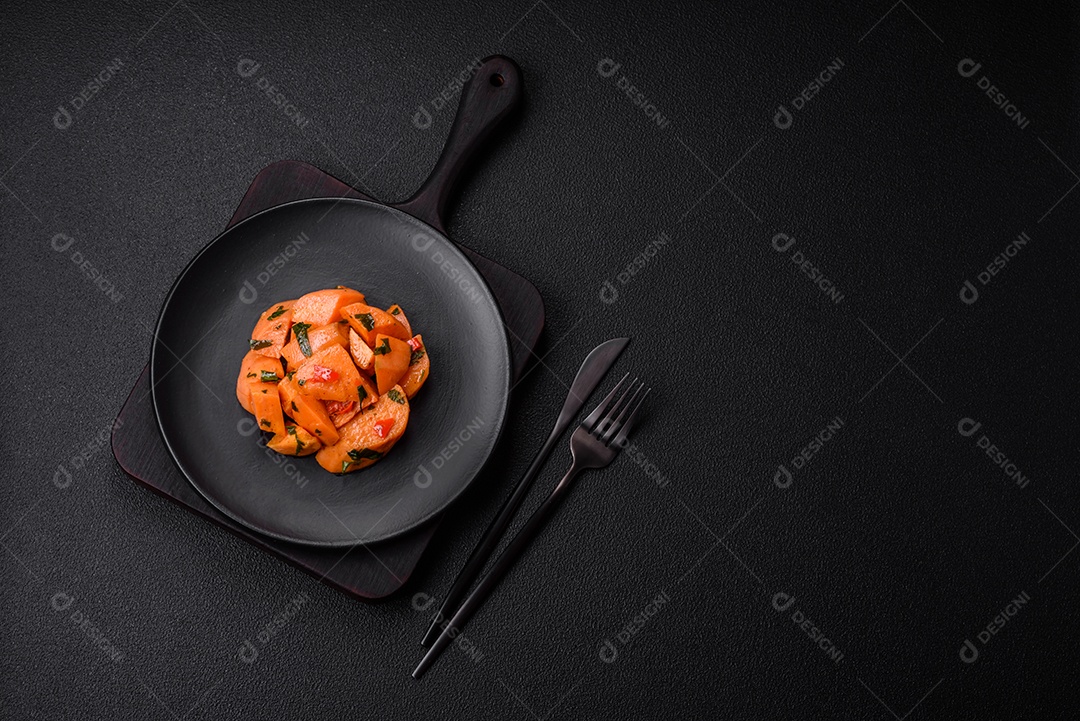 Deliciosa batata-doce cozida com cubos de sal, especiarias e ervas em uma placa cerâmica sobre um fundo escuro de concreto