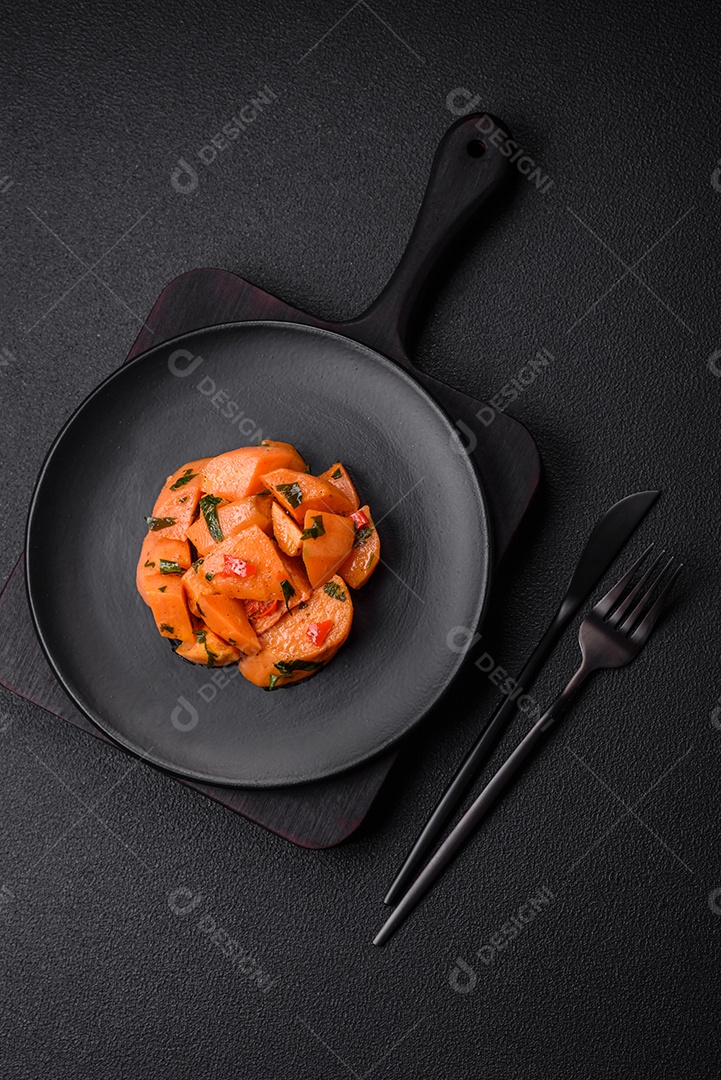 Deliciosa batata-doce cozida com cubos de sal, especiarias e ervas em uma placa cerâmica sobre um fundo escuro de concreto