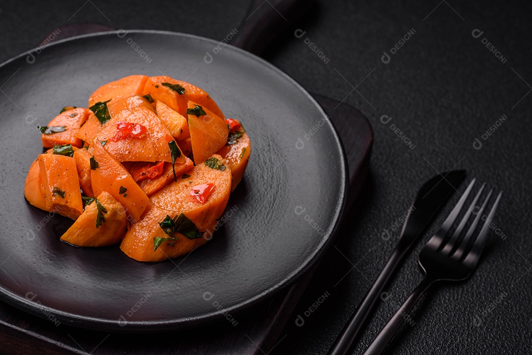 Deliciosa batata-doce cozida com cubos de sal, especiarias e ervas em uma placa cerâmica sobre um fundo escuro de concreto