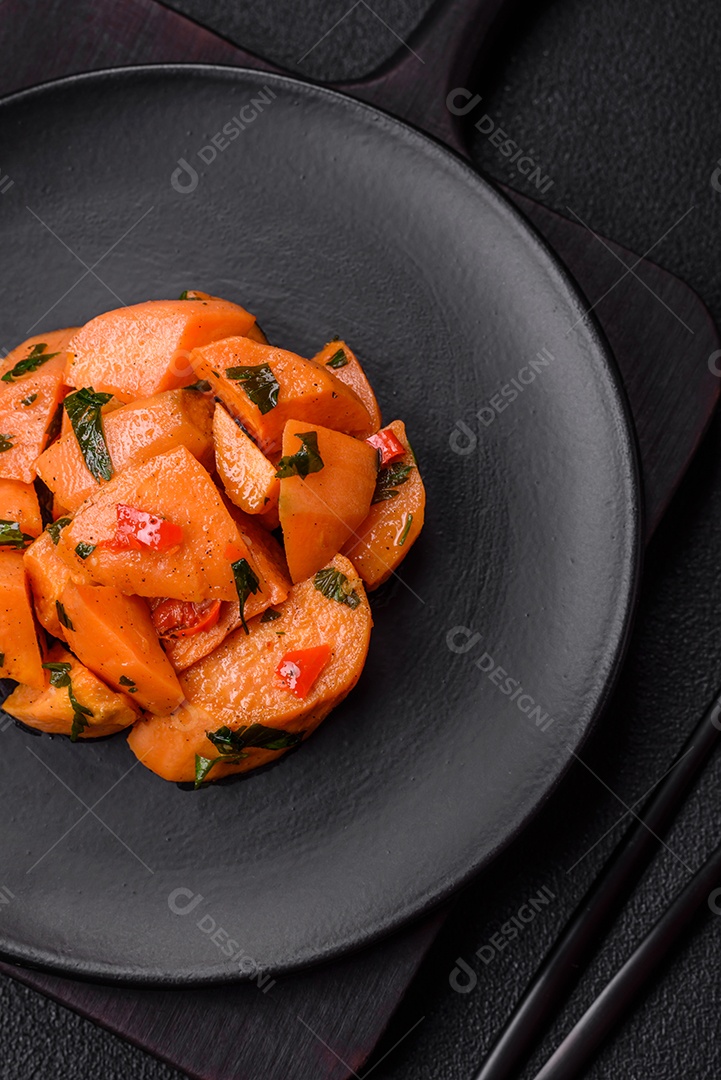 Deliciosa batata-doce cozida com cubos de sal, especiarias e ervas em uma placa cerâmica sobre um fundo escuro de concreto