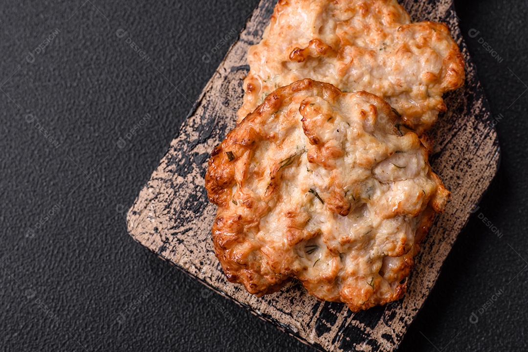 Deliciosa costeleta de frango frito ou carne de porco frita à milanesa com sal, especiarias e ervas sobre um fundo escuro de concreto